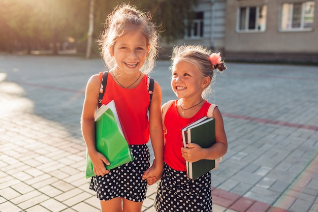 Heureuse soeurs portant des sacs à dos et tenant des livres