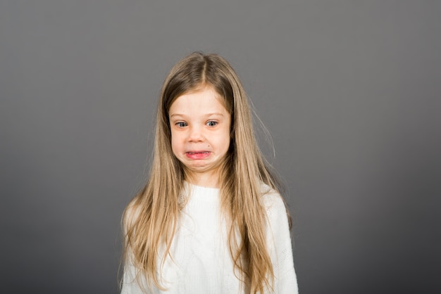 Heureuse surprise belle petite fille enfant à la recherche d'appareil photo sur fond gris.