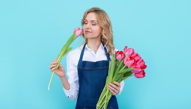 Heureuse Vendeuse De Fleurs Femme En Tablier Avec Des Fleurs De Tulipes Printanières Sur Fond Bleu