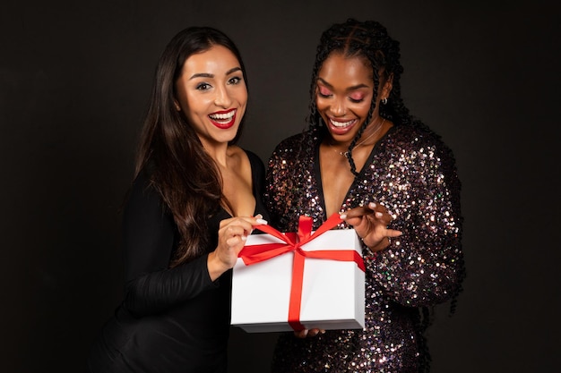 Heureuses belles jeunes copines multiethniques tenant une boîte à cadeaux