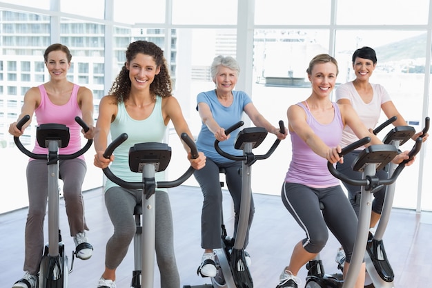 Heureuses femmes qui travaillent à la classe de spinning