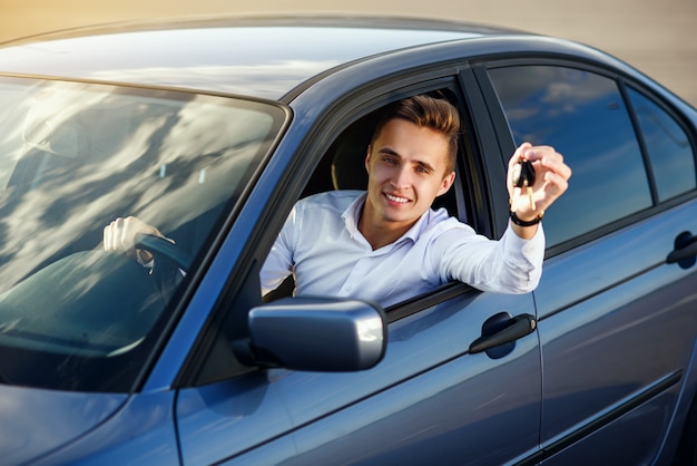 Heureux acheteur détenant les clés de voiture à l'intérieur de son nouveau véhicule