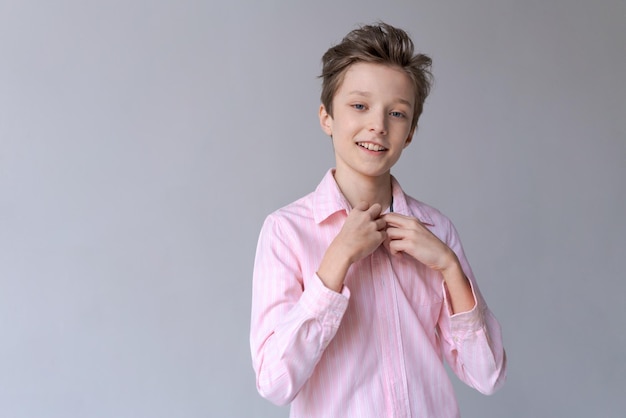 Heureux adolescent confiant en chemise rose élégante à la recherche d'un sourire digne de confiance