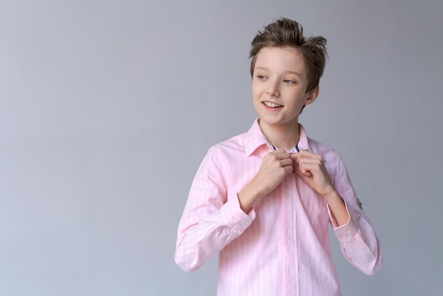 Heureux adolescent confiant en chemise rose élégante à la recherche d'un sourire digne de confiance