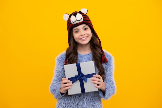 Heureux adolescent émotions positives et souriantes de l'adolescente Enfant en vêtements d'hiver tenant un cadeau pour le Nouvel An ou Noël