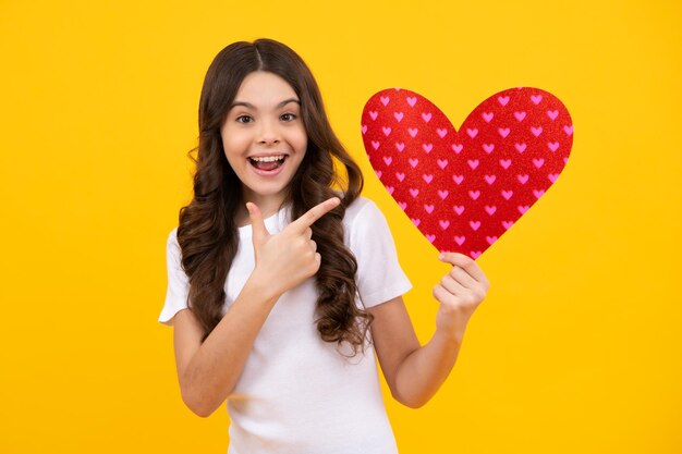 Heureux adolescent émotions positives et souriantes d'une adolescente sur fond jaune Belle enfant fille 12 13 14 ans avec forme coeur amour vacances et symbole de la Saint-Valentin Saint-Valentin ou jour d'anniversaire