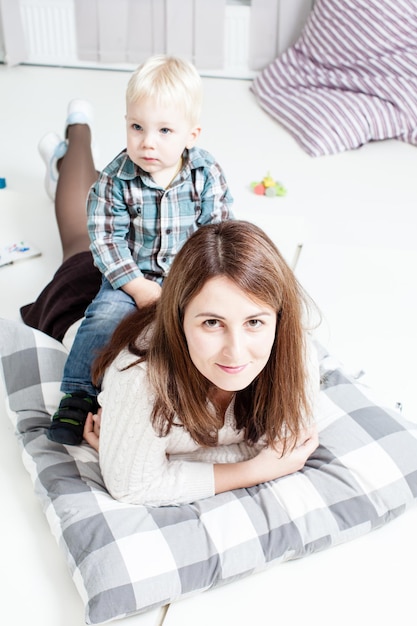 Heureux adorable petit garçon assis sur le dos de sa mère