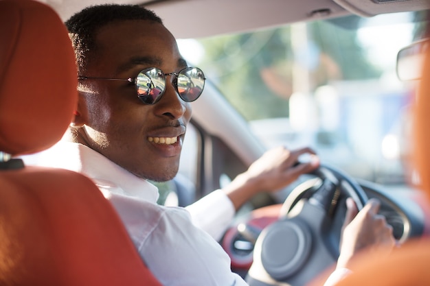 Heureux afro-américain conduisant une voiture, en été