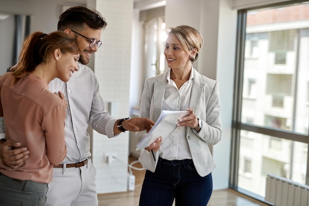 Heureux agent immobilier et jeune couple faisant des projets dans un nouvel appartement