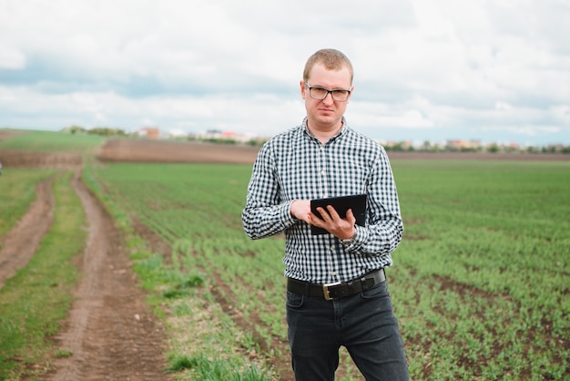 Heureux agriculteur dans les champs avec un ordinateur portable