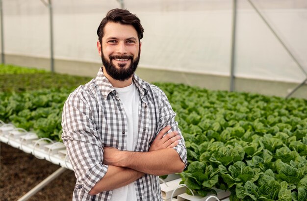 Heureux agriculteur près de laitue en serre