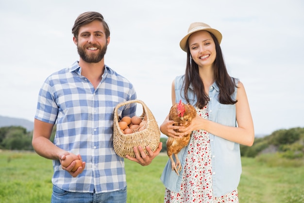 Heureux agriculteurs tenant le poulet et les oeufs