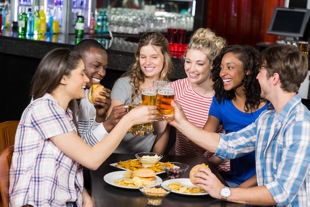 Heureux amis buvant un verre et un hamburger