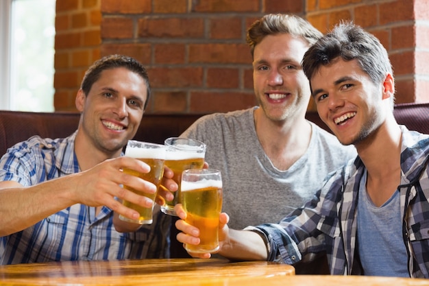 Heureux amis griller avec des pintes de bière dans un bar