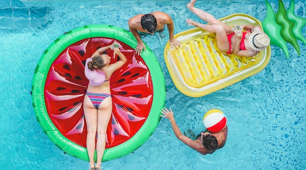 Heureux amis jouant avec air lilo ball à l'intérieur de la piscine