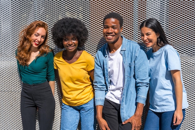 Heureux amis multiethniques dans la ville sur un mur gris jeunes mannequins souriants