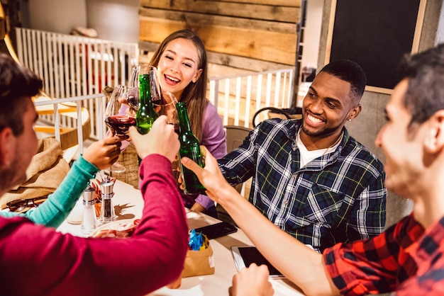 Heureux amis multiraciaux, grillage de la bière à l'intérieur au pub de la brasserie