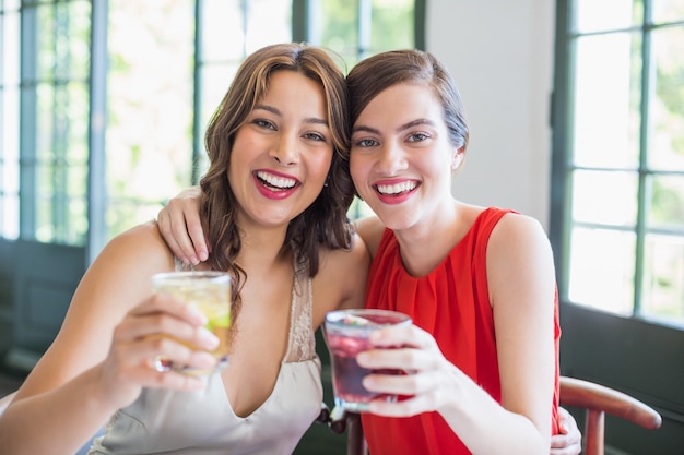 Heureux amis s'embrassant tout en tenant des verres à cocktail