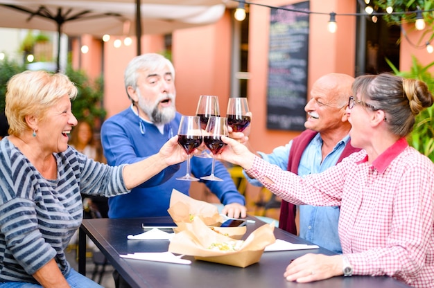 Heureux amis senior souriant et grillage du vin rouge au bar