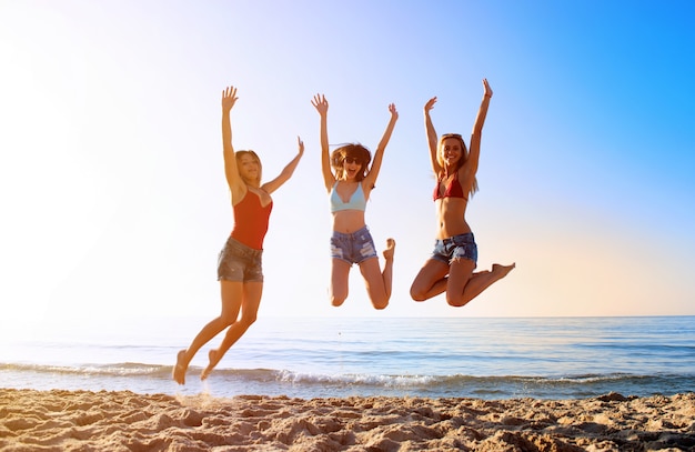 Heureux amis souriants sautant à la plage