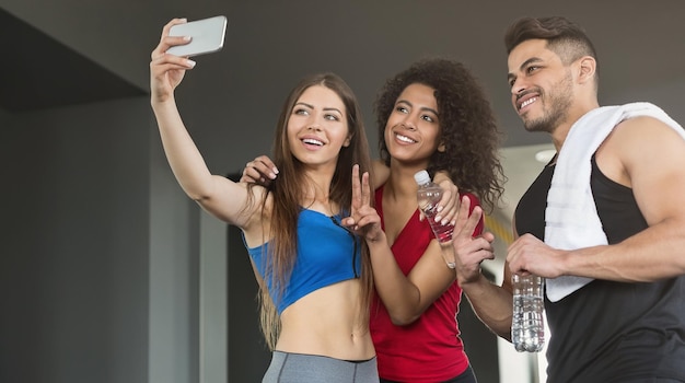 Heureux amis sportifs prenant selfie dans une salle de sport après l'entraînement