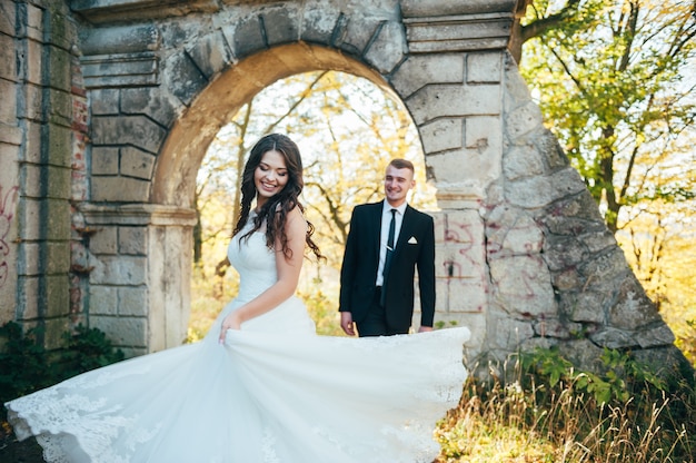 Heureux et amoureux mariés marchent dans le parc d'automne le jour de leur mariage