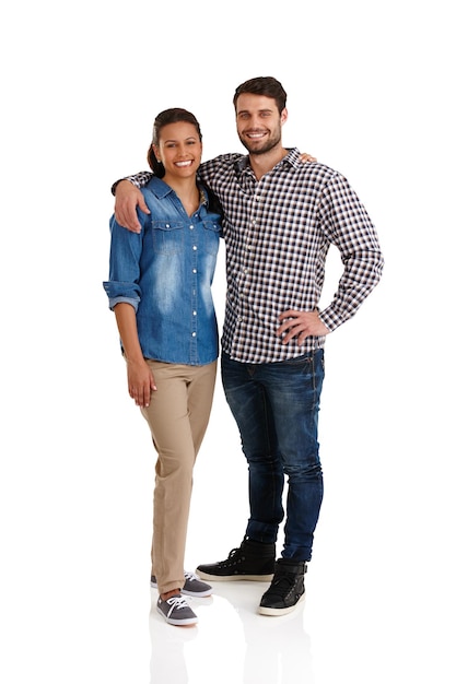 Heureux et amoureux Studio portrait d'un jeune couple affectueux debout avec leurs bras l'un autour de l'autre isolé sur blanc