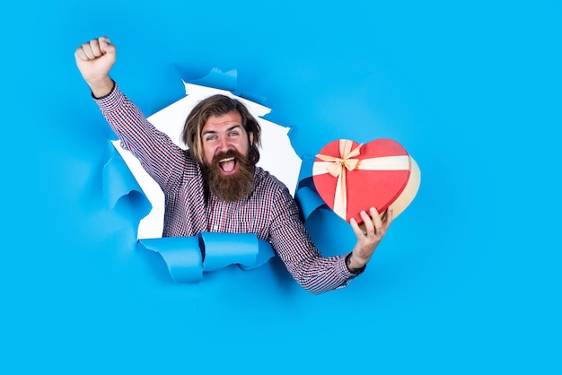 Heureux barbu mature a les cheveux longs avec une boîte-cadeau pour les achats de vacances