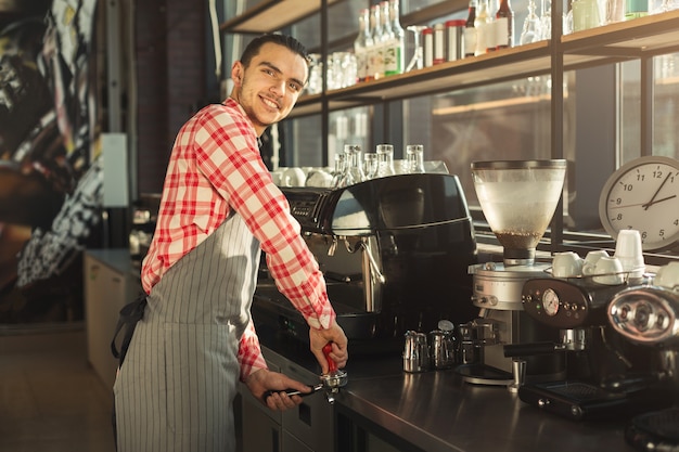 Heureux barman faisant un expresso dans une machine à café moderne. Homme préparant une boisson tonifiante. Concept de brassage de café pour les petites entreprises et les professionnels