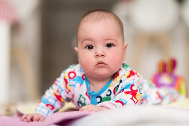 heureux beau bébé garçon nouveau-né allongé sur des couvertures colorées tout en jouant aux premiers jeux sur le sol à la maison