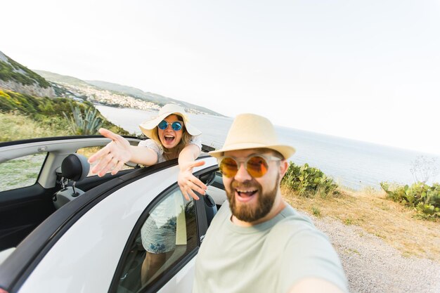 Heureux beau couple amoureux prenant un selfie portrait au volant d'une voiture décapotable sur la route en vacances Voitures de location et vacances