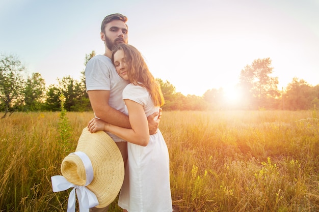 Heureux beau couple câlins dans le parc au coucher du soleil.