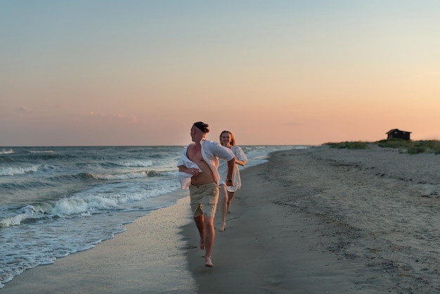 heureux beau couple marchant au coucher du soleil le long du bord de mer