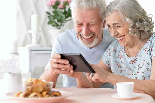 Heureux beau couple de personnes âgées à l'aide de tablette à la maison