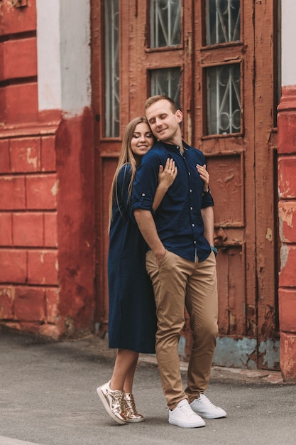 Heureux beau jeune couple sur fond de vieilles portes rouges. Notion de famille heureuse