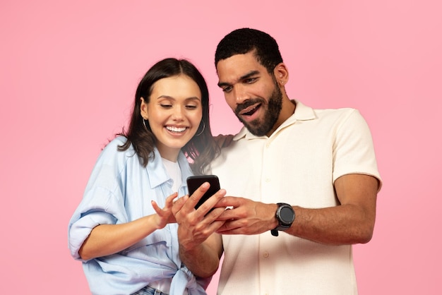 Heureux beau jeune couple regardant l'écran brillant du smartphone