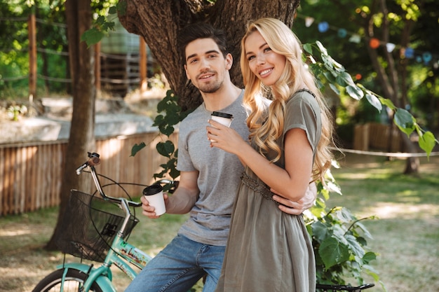 Heureux beau jeune couple se reposer avec du café et regardant la caméra à l'extérieur