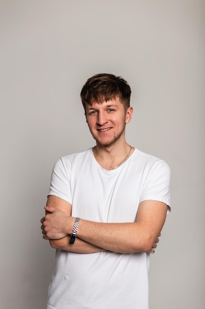 Heureux beau jeune homme avec un sourire dans un T-shirt blanc en studio