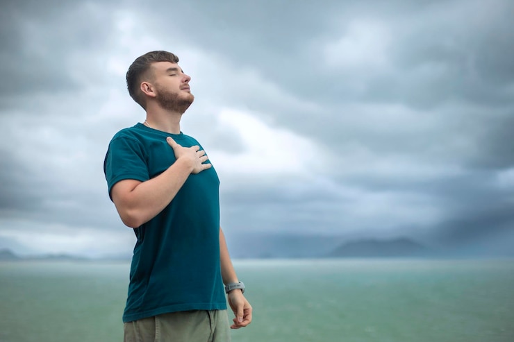 Photo heureux beau mec libre jeune calme détendu homme insouciant voyageur avec les mains levées ouvertes profiter de la mer vue sur l'océan personne se sentant bien respirer profondément profondément l'air frais liberté voyage bonheur concept