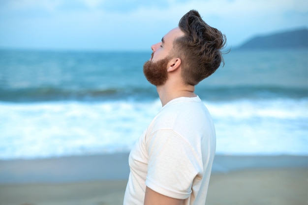 Heureux beau mec libre jeune calme détendu homme insouciant voyageur profiter de la mer sur la plage vue sur l'océan