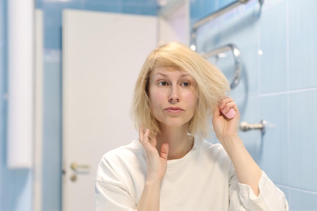 Heureux beau modèle féminin peigne ses cheveux avec une brosse à cheveux, a un teint bien soigné et une peau saine. Concept de routine de soins capillaires et de beauté