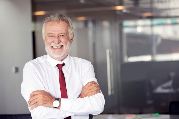 Photo heureux beau vieil homme d'affaires debout et souriant au bureau