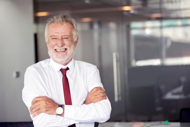 Heureux beau vieil homme d&#39;affaires debout et souriant au bureau