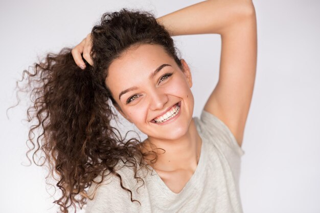 Heureux et beau visage de jeune femme brune souriante aux cheveux bouclés Closeup portrait