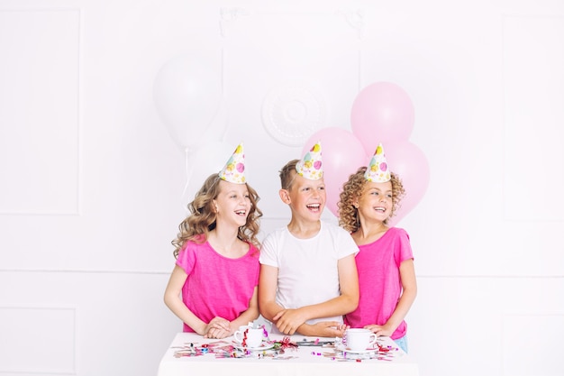 Heureux beaux enfants mignons sourient à la fête de vacances avec des ballons et des confettis ensemble