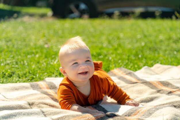 Heureux bébé allongé sur la couverture sur l'herbe ensoleillée Enfant en plein air