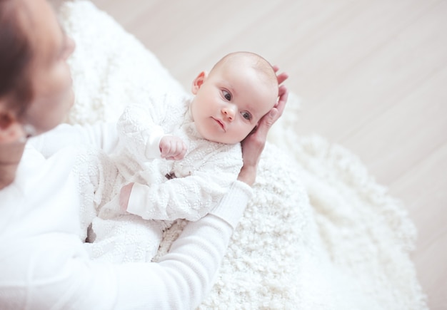 Heureux bébé allongé sur les mains de la mère dans la chambre