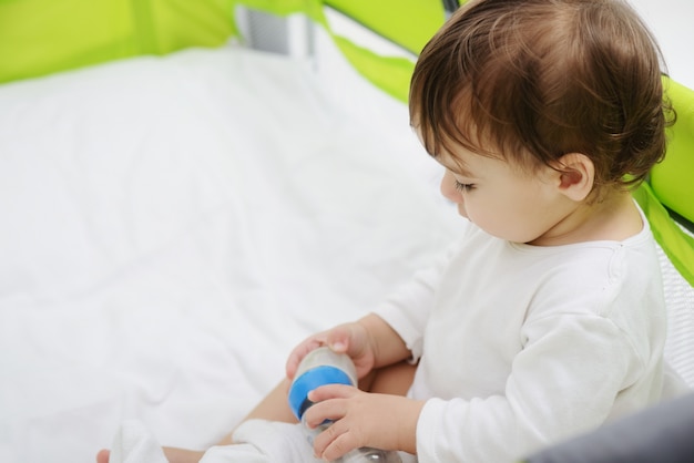 Heureux bébé assis sur le lit en jouant avec des jouets