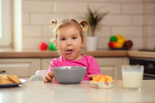 Heureux bébé assis à la table dans la cuisine et manger avec un appétit