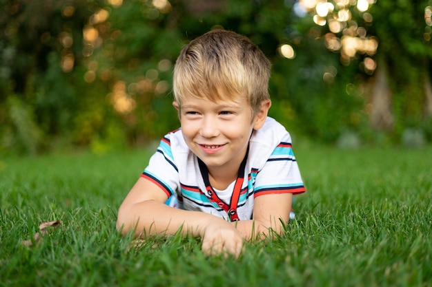 Heureux bébé blond aux yeux bleus allongé sur l'herbe souriant loisirs de plein air vacances enfance heureuse